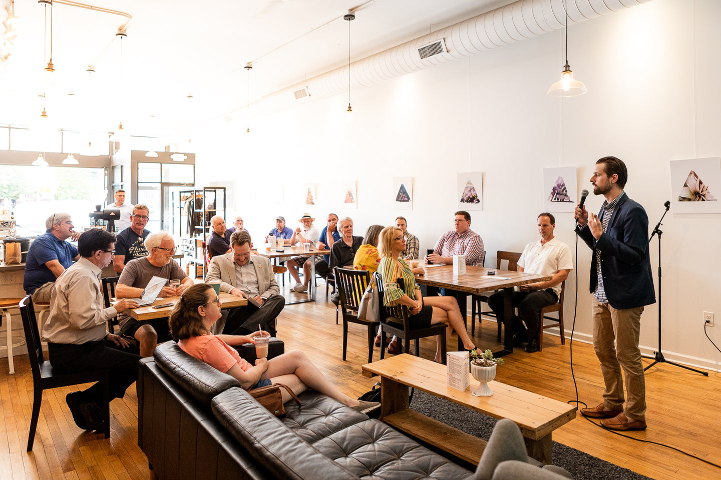 Group of people in a casual meeting or workshop setting with a speaker at the front.
